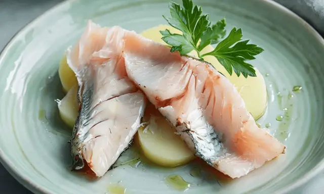 Lubina a la sal Thermomix: jugosos filetes de pescado sobre patatas, decorados con perejil fresco y un toque de aceite.