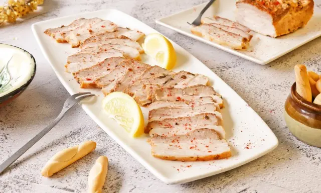 Chicharrón de Cádiz en lonchas, servido con limón y picos. Un plato que evoca el sabor de Andalucía.