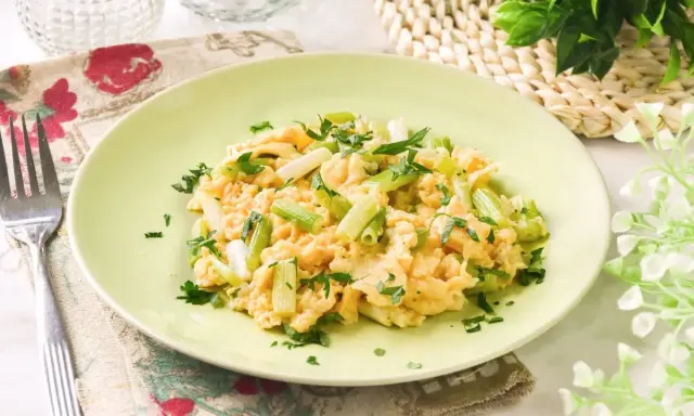 Revuelto de ajetes con perejil fresco, servido en un plato verde claro.