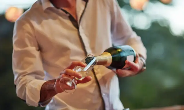 Un hombre sirve cava español en una copa.
