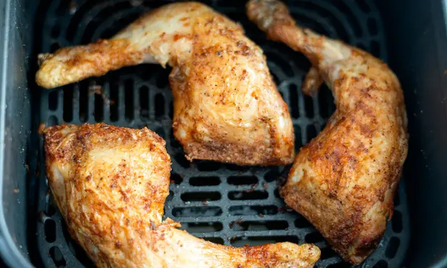 Muslos de pollo dorados y jugosos en la freidora de aire, listos para disfrutar.