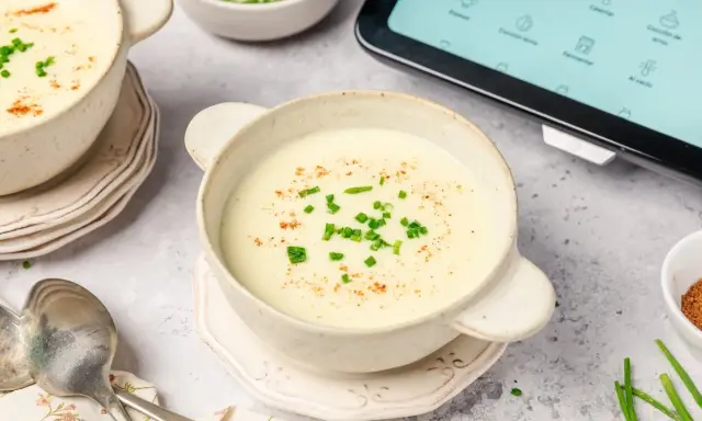 Crema de patatas y puerros lista en la vichisua Thermomix, servida en cuencos con cebollino y pimentón.