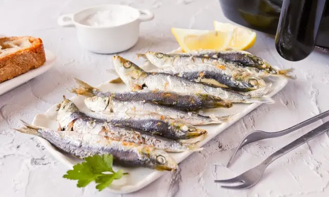 Sardinas en freidora de aire, doradas y crujientes, listas para disfrutar con limón y pan.