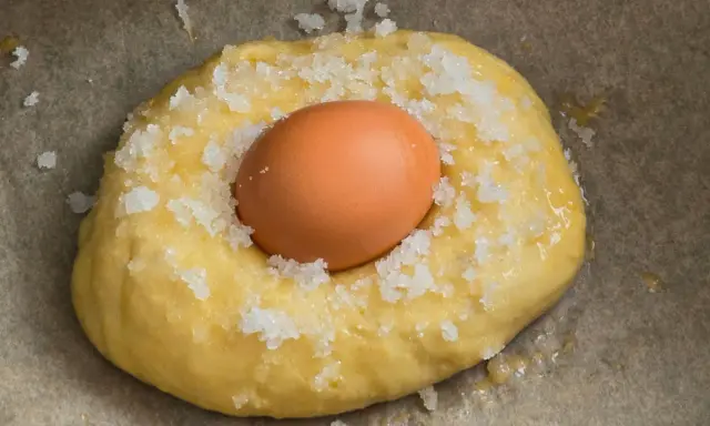 Masa para receta mona de pascua esponjosa, con un huevo crudo incrustado y espolvoreada con azúcar.