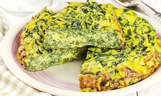 Tortilla de espinacas y queso, dorada y esponjosa, servida en un plato.