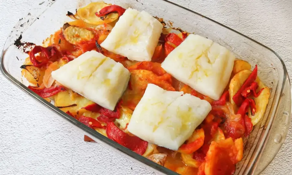 Bacalao al horno con patatas panaderas, cebolla y pimientos. Un plato casero listo para disfrutar.