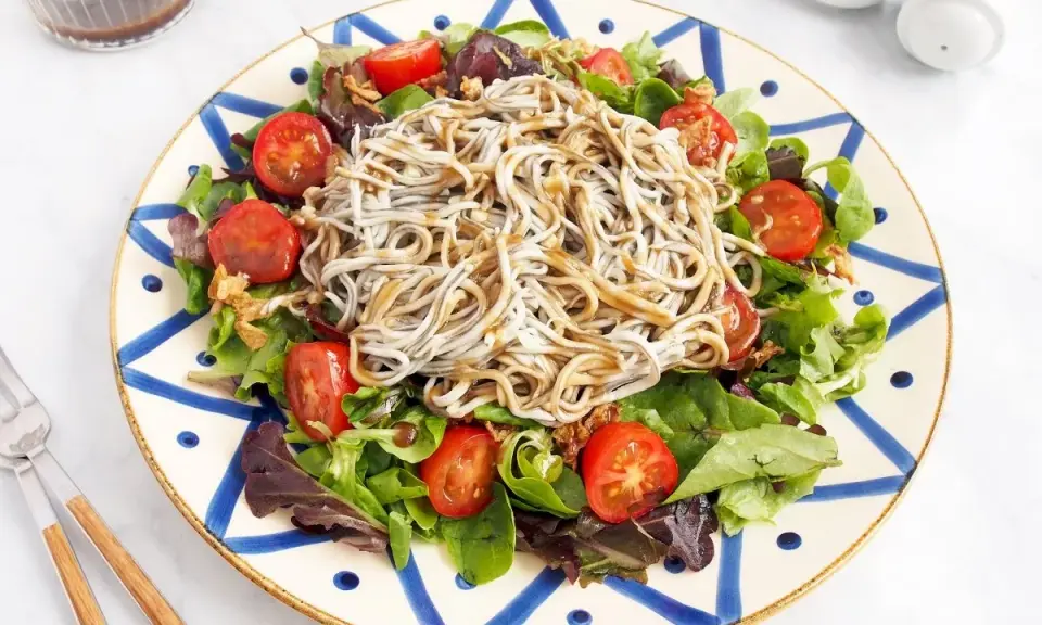 Deliciosa ensalada de gulas con tomates cherry y hojas verdes, servida en un plato decorado.