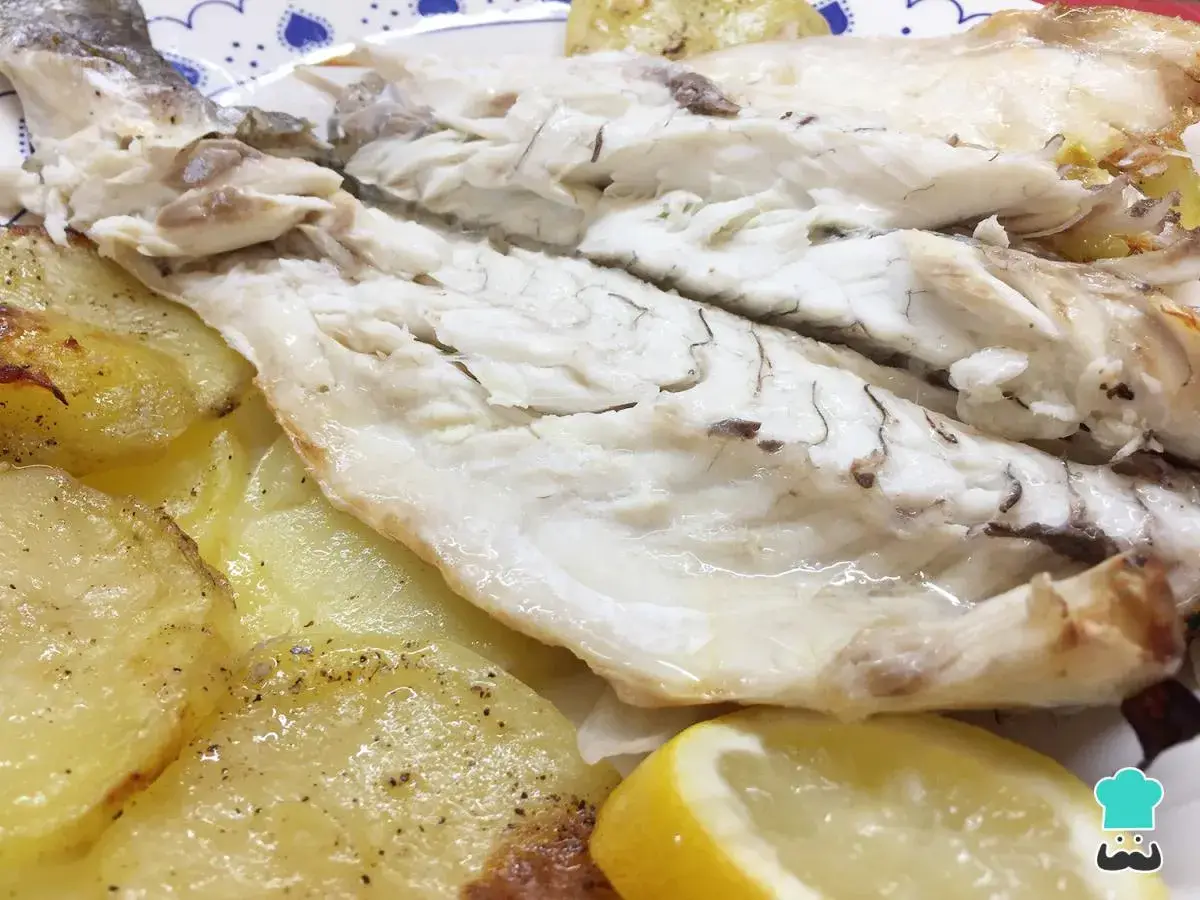 Lubina al horno jugosa y tierna, acompañada de patatas doradas y una rodaja de limón. ¡Un plato delicioso y saludable!