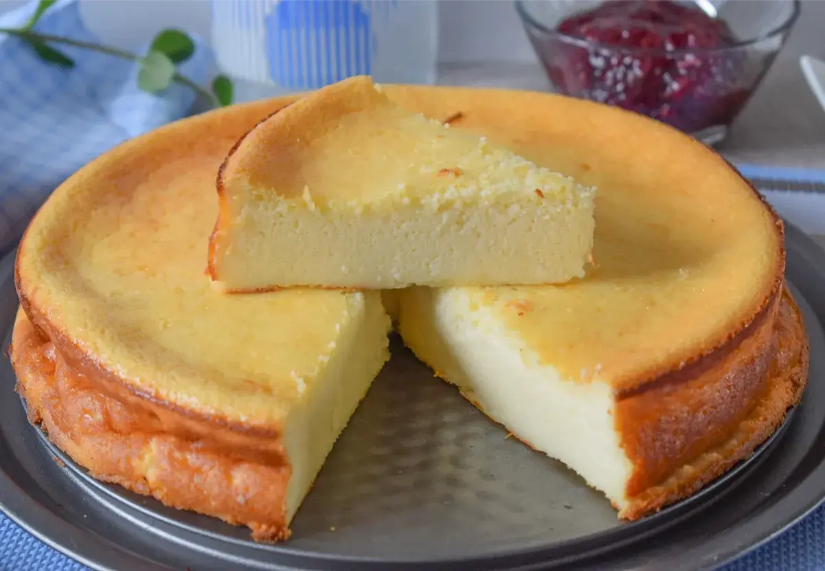 Una deliciosa tarta de queso recién horneada, con una rebanada servida encima. Perfecta para compartir.