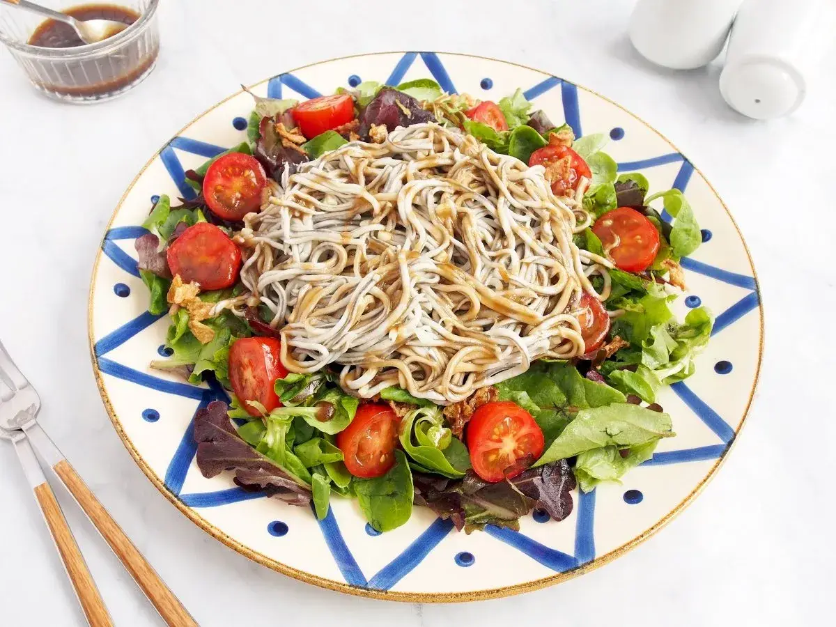 Deliciosa ensalada de gulas con tomates cherry y hojas verdes, servida en un plato decorado.