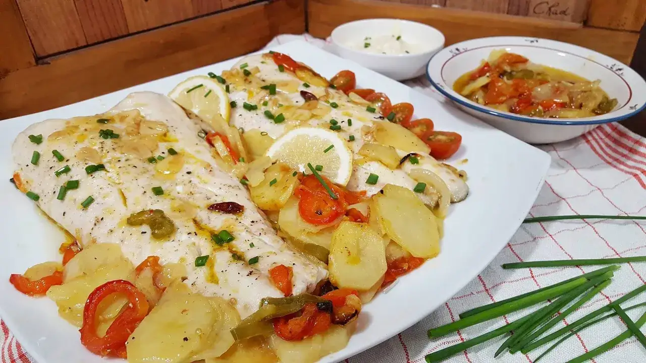Deliciosa merluza al horno con patatas, pimientos y tomates. Un plato principal perfecto.