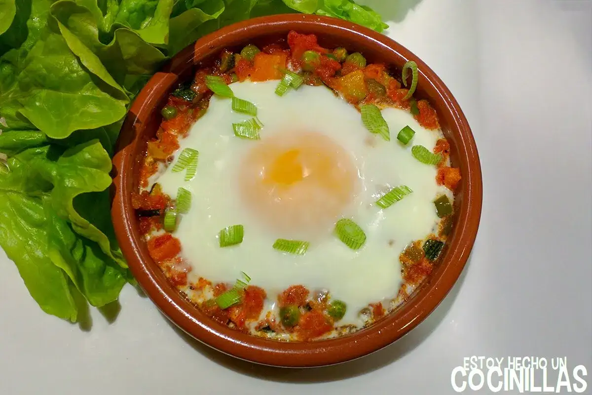 Un huevo escalfado sobre un sofrito de verduras, con cebolleta picada. Un plato que recuerda al hervido valenciano, acompa&ntilde;ado de hojas de lechuga fresca.