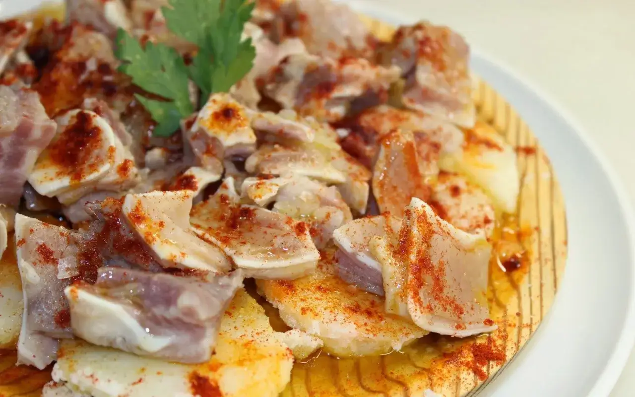 Oreja a la gallega, trozos de oreja de cerdo cocida, aderezada con piment&oacute;n y aceite, servida sobre patatas.