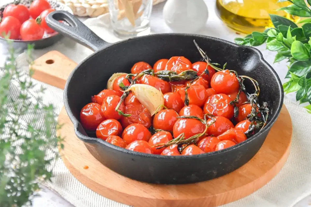 Tomates cherry confitados en sart&eacute;n de hierro fundido, con ajo y hierbas arom&aacute;ticas, listos para disfrutar.