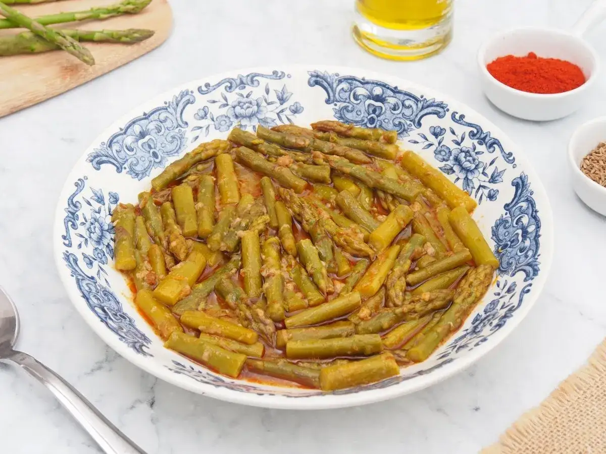 Plato de esparragos esparragados con ajo y piment&oacute;n, acompa&ntilde;ado de aceite de oliva y especias.