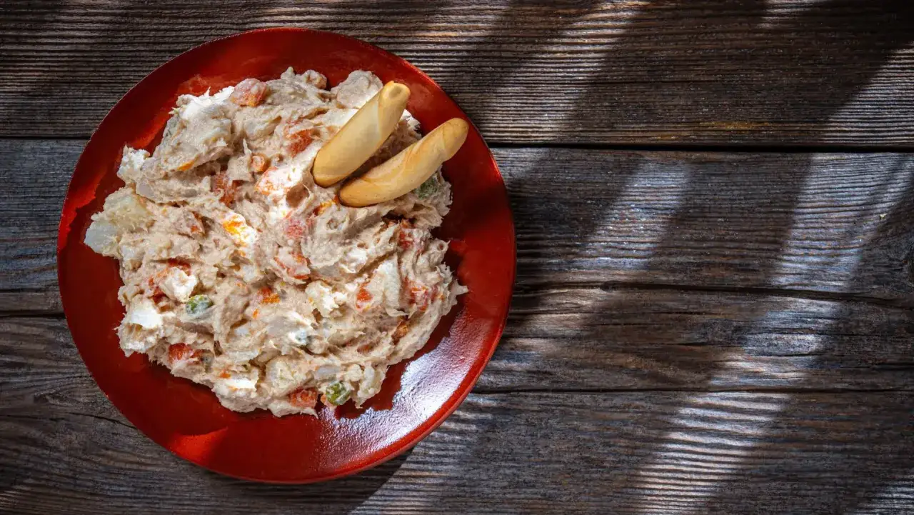 Ensaladilla rusa cremosa en plato rojo con picos. &iquest;Cuanto dura la ensaladilla rusa en la nevera?