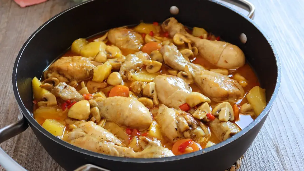 Pollo mechado jugoso en salsa con papas, champi&ntilde;ones y zanahorias en una sart&eacute;n.