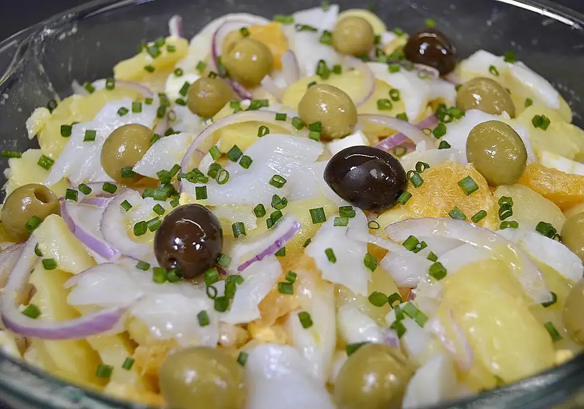 Ensalada malagueña con patatas, huevo duro, bacalao desmigado, aceitunas verdes y negras, cebolla morada y cebollino picado.