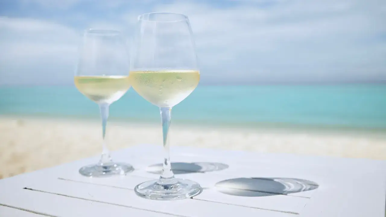 Dos copas de vino blanco fr&iacute;o sobre una mesa blanca en la playa. &iquest;El albari&ntilde;o es dulce o seco?