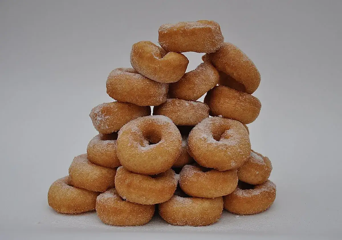 Mont&oacute;n de rosquillas de palo cubiertas de az&uacute;car, apiladas en forma de pir&aacute;mide sobre un fondo blanco.