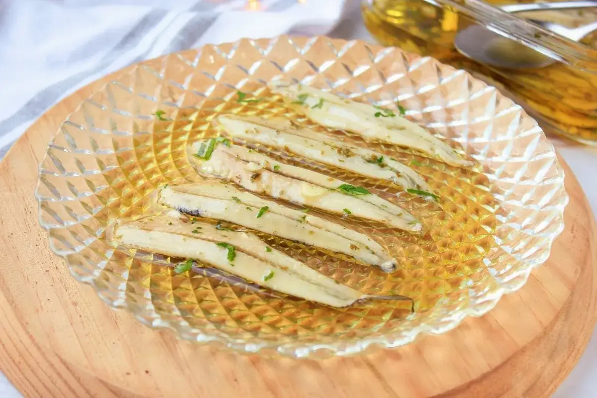 Boquerones en vinagre, la receta de la abuela, servidos en un plato de cristal con perejil picado.