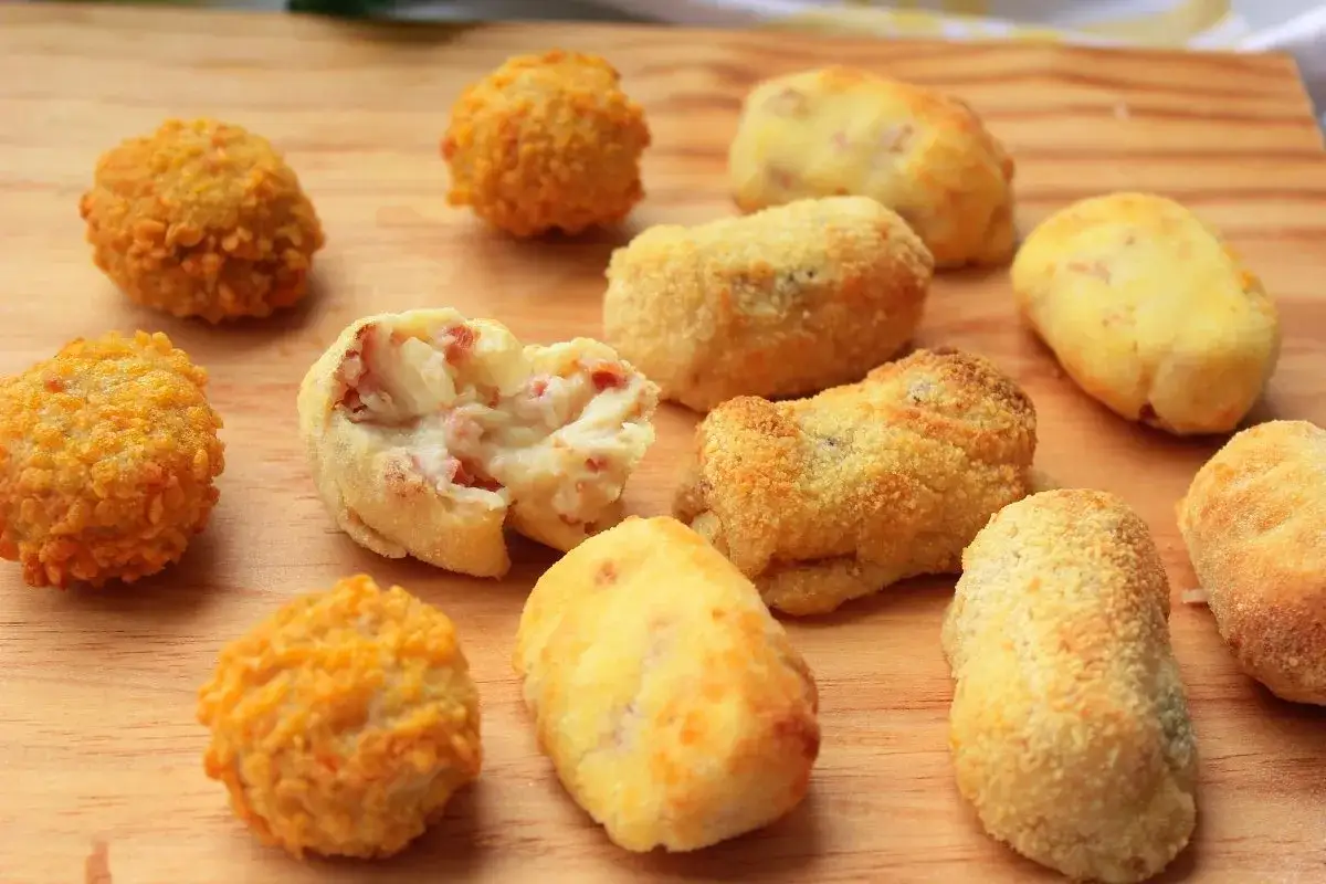 Croquetas caseras en freidora de aire, algunas redondas y crujientes, otras alargadas y doradas, con un interior cremoso y trocitos de jam&oacute;n.