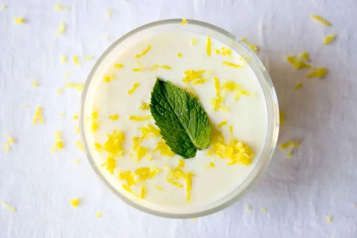 Delicioso mousse de lim&oacute;n Thermomix, decorado con ralladura de lim&oacute;n y una hoja de menta fresca.