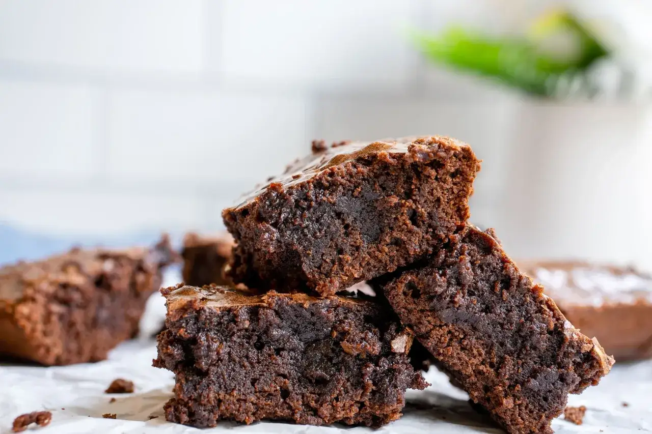 Deliciosos trozos de brownie sin gluten apilados, con una textura h&uacute;meda y chocolateada.