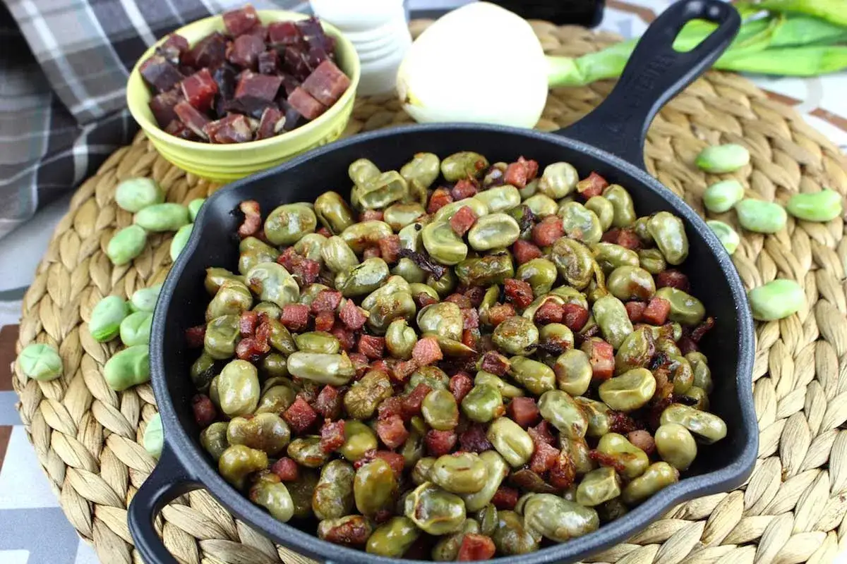 Habas tiernas salteadas con trocitos de jam&oacute;n crujiente en una sart&eacute;n de hierro fundido. Un plato sencillo y delicioso.