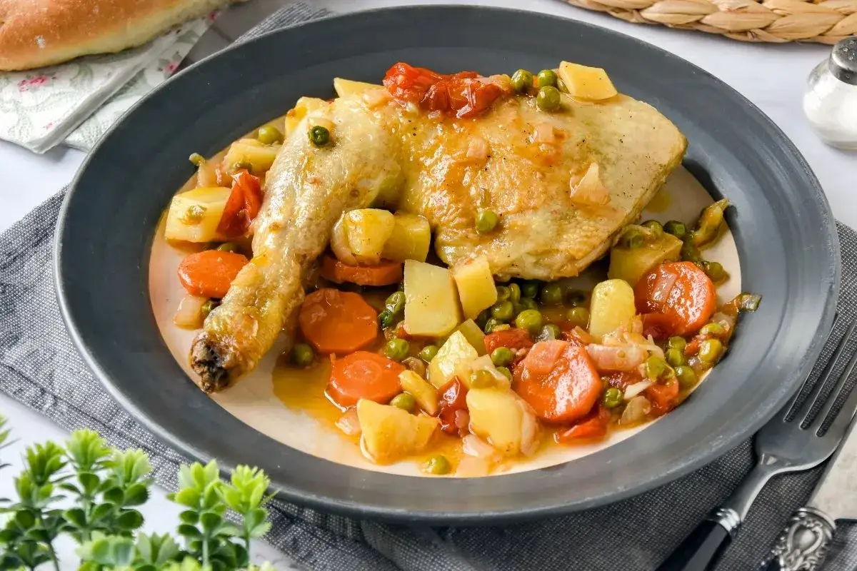 Delicioso pollo a la jardinera con patatas, zanahorias y guisantes en una salsa sabrosa.