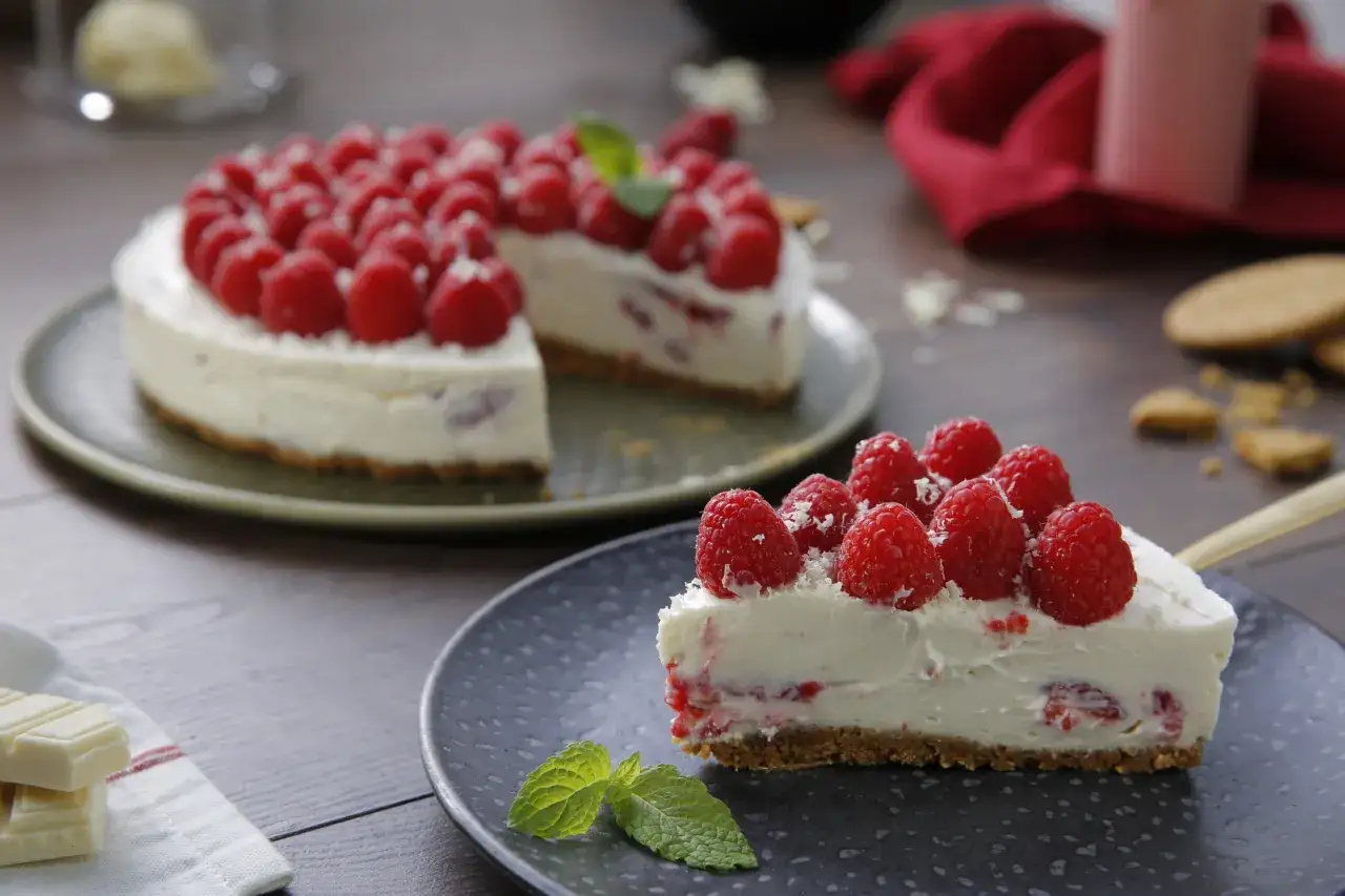 Deliciosa tarta de chocolate blanco con frambuesas frescas y menta. Un trozo perfecto para disfrutar.