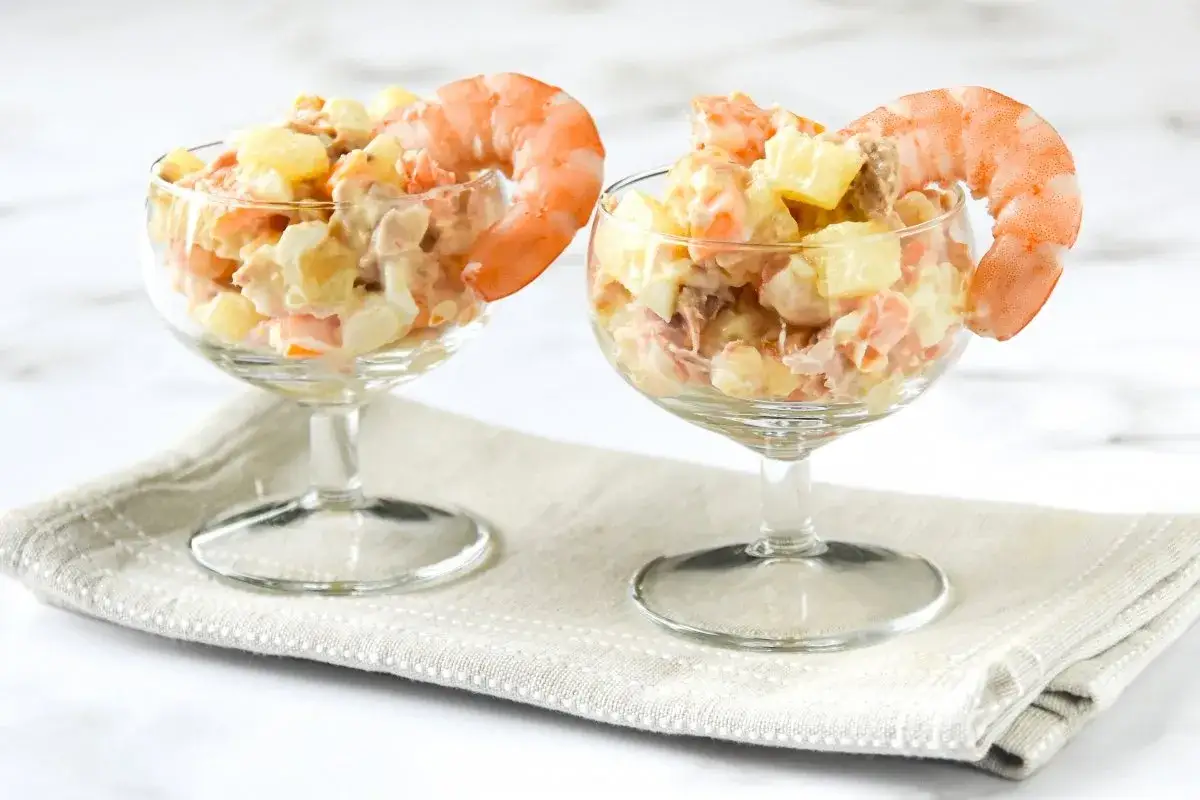Dos copas de ensaladilla de gambas, decoradas con gambas enteras, sobre una servilleta.