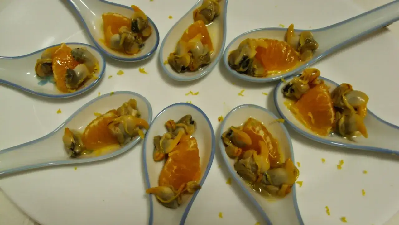 Cucharitas con ceviche de berberechos y gajos de naranja, un bocado fresco y c&iacute;trico.
