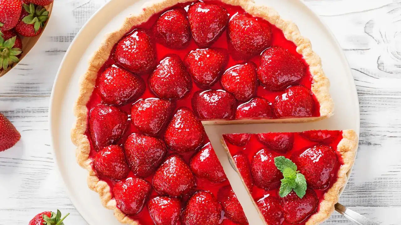 Deliciosa tarta de fresas cubierta con gelatina brillante y fresas frescas. Una porci&oacute;n se ha cortado, revelando la jugosa fruta.