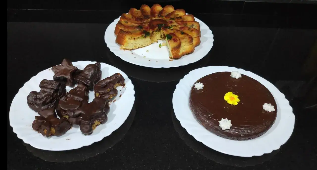 Tres postres: bizcocho borracho con frutas confitadas, galletas ba&ntilde;adas en chocolate y un pastel de chocolate decorado.