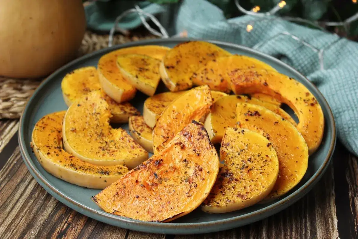 Rodajas de calabaza a la plancha, doradas y especiadas, servidas en un plato azul. Un plato sencillo y delicioso.
