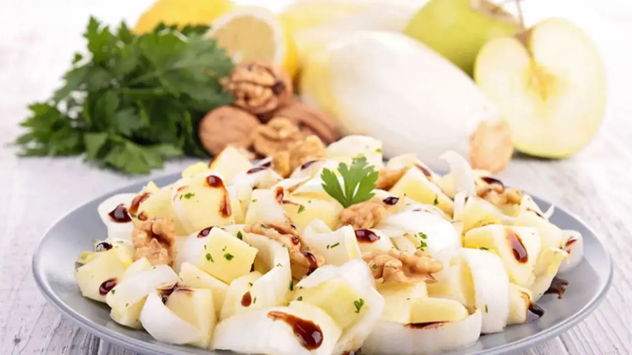 Deliciosa ensalada de endivias con trozos de manzana, nueces y un toque de aderezo oscuro.