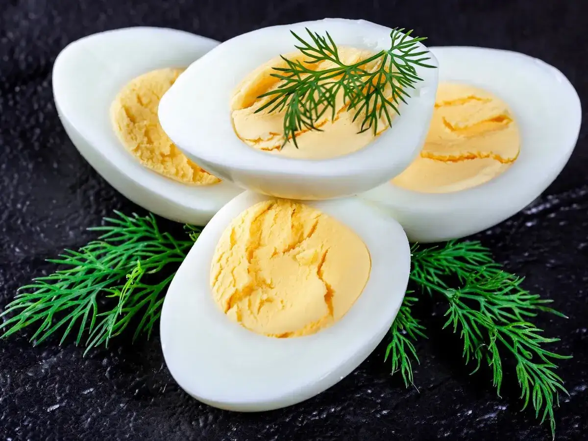 Huevos duros cortados por la mitad, con yemas amarillas y eneldo fresco. Perfectos para aprender como cocer huevos duros y que se pelen bien.