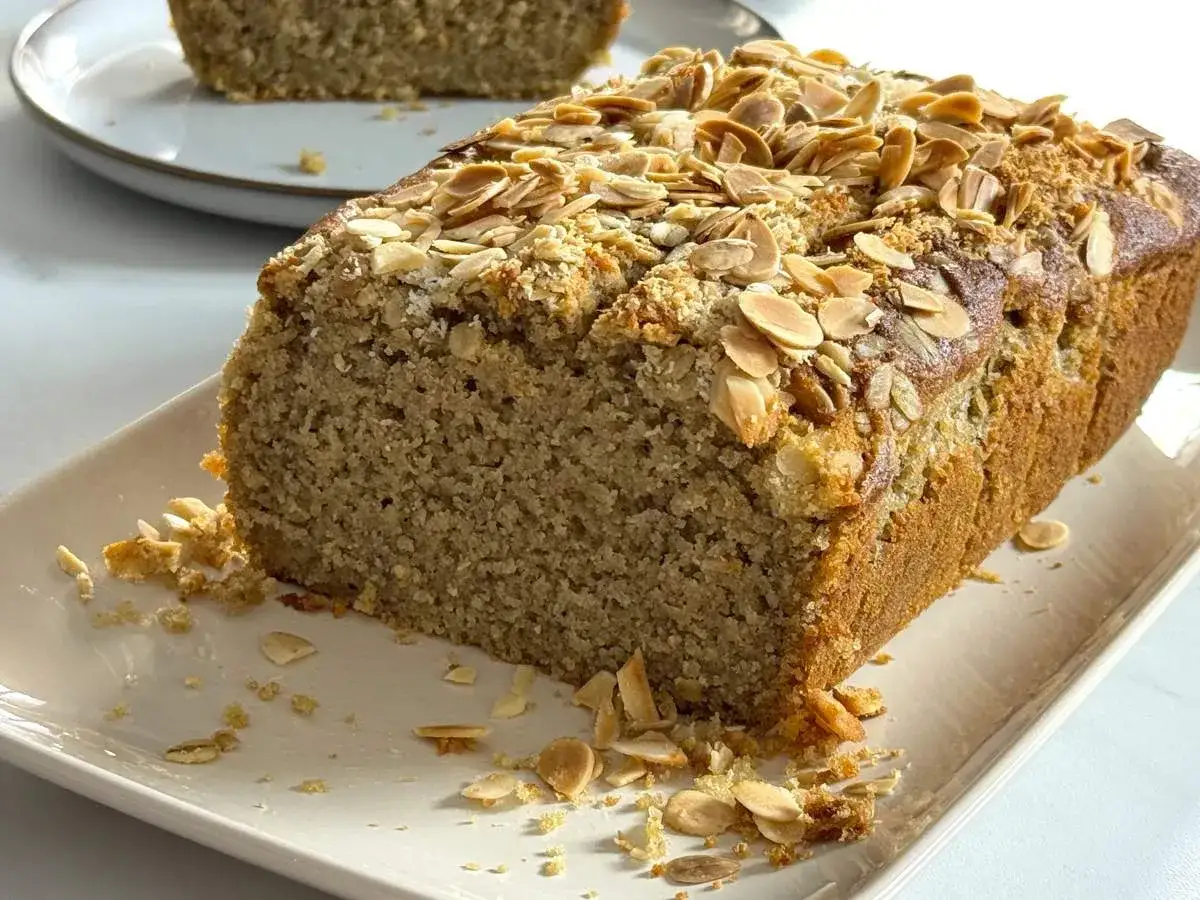 Un delicioso bizcocho de avena, dorado y cubierto de almendras laminadas, listo para disfrutar.