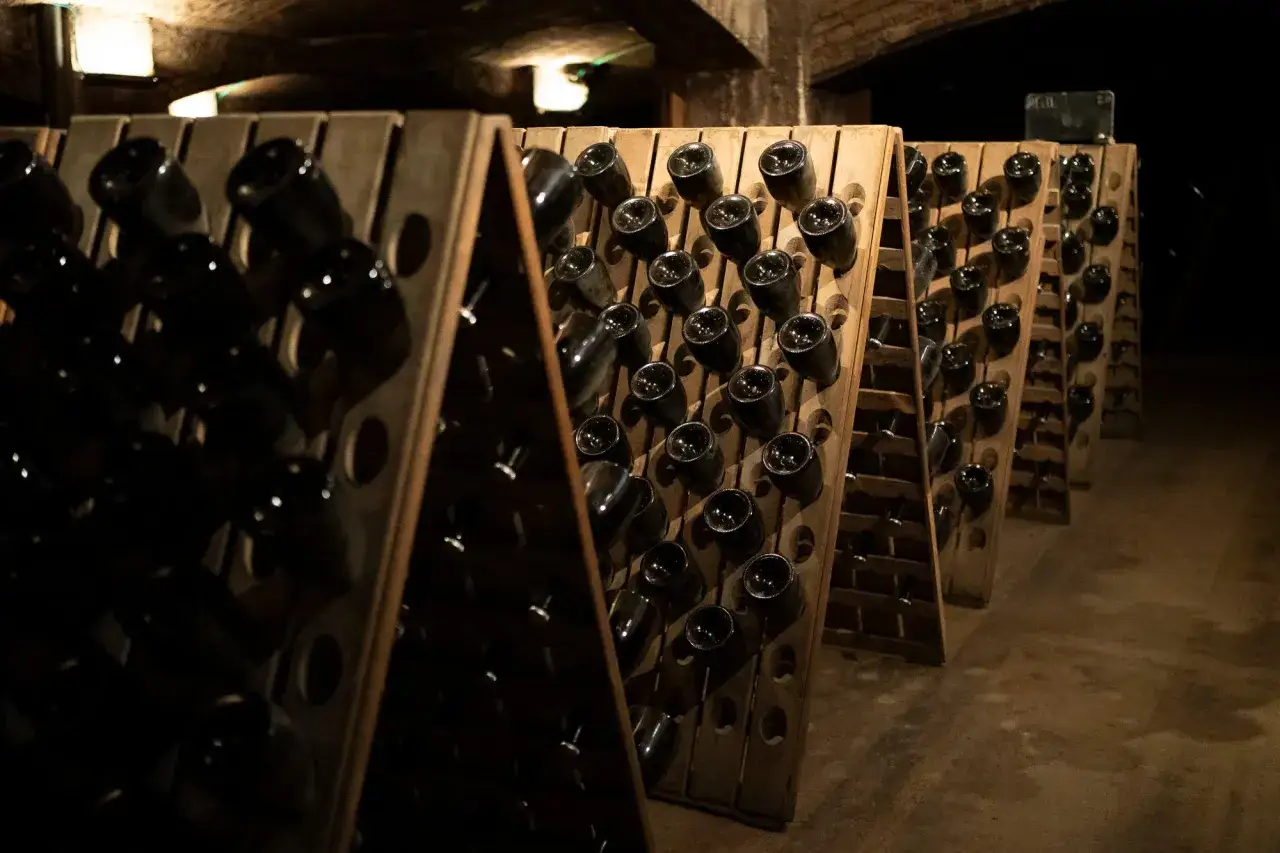 Botellas de cava espagnol en pupitres de madera en una bodega subterr&aacute;nea.