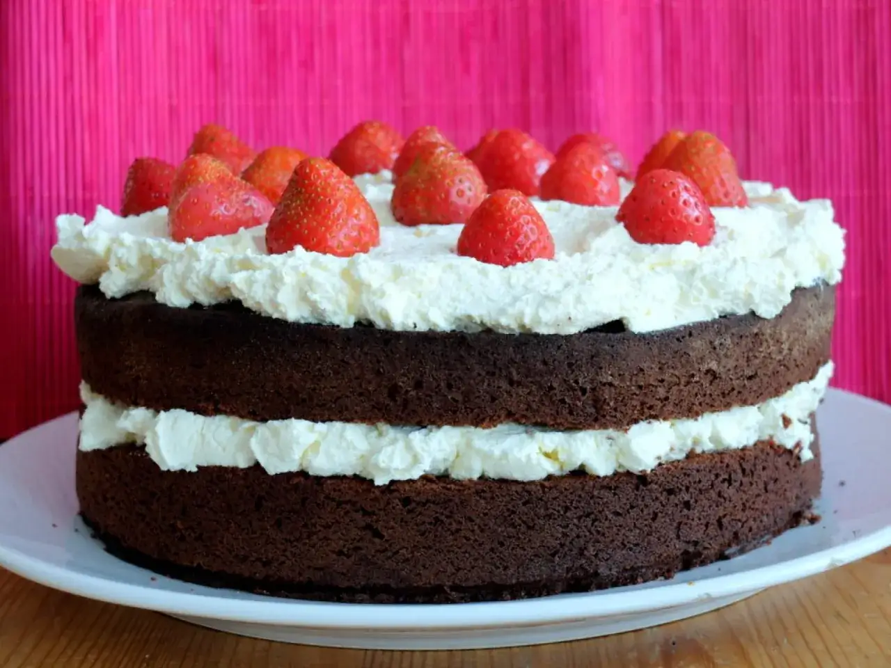 Pastel de chocolate de dos capas cubierto con crema batida y fresas frescas. &iexcl;Una delicia irresistible!