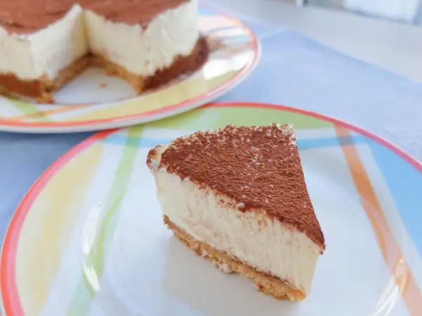 Delicioso cheesecake con cacao espolvoreado, listo para disfrutar. Una receta perfecta para cualquier ocasión.